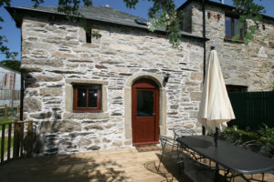 the exterior and decking with garden furniture and parasol of children friendly Humpty Dumpty cottage Cornwall