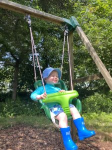 toddler enjoying a swing in the orchard on a farm holiday
